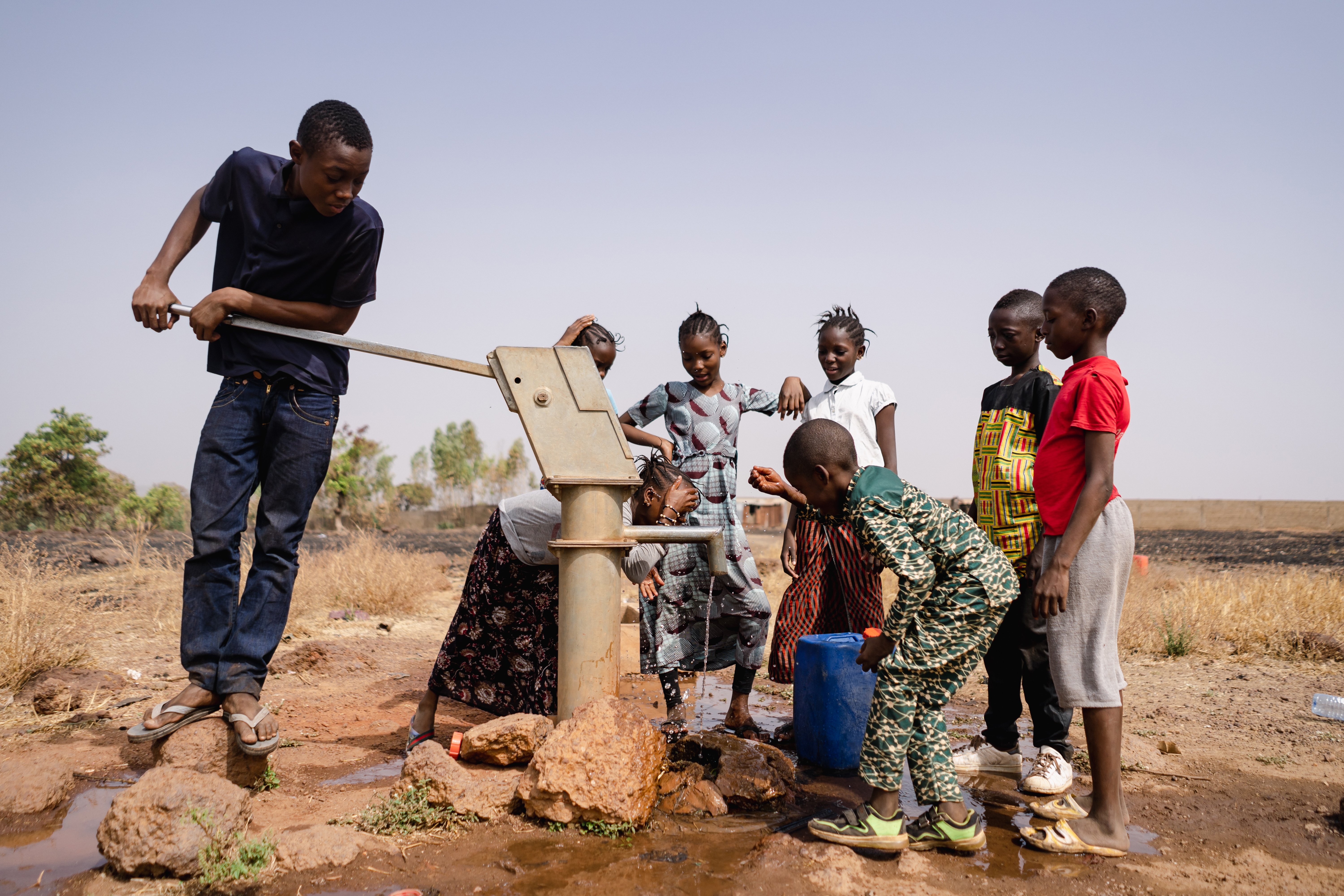 African school age children gathering around a sub saharian village faucet, Riccardo Mayer, Shutterstock